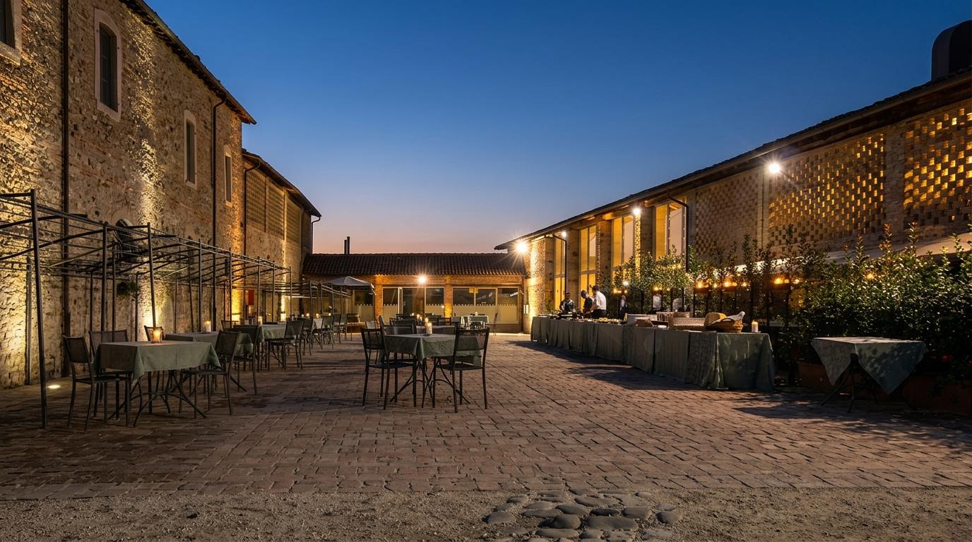 La corte in mattoni del Ristorante Corte di Giarola illuminata al crepuscolo, con tavoli apparecchiati e buffet