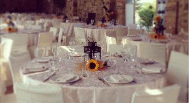 Tavolo rotondo apparecchiato con girasole e lanterna nella sala del ristorante