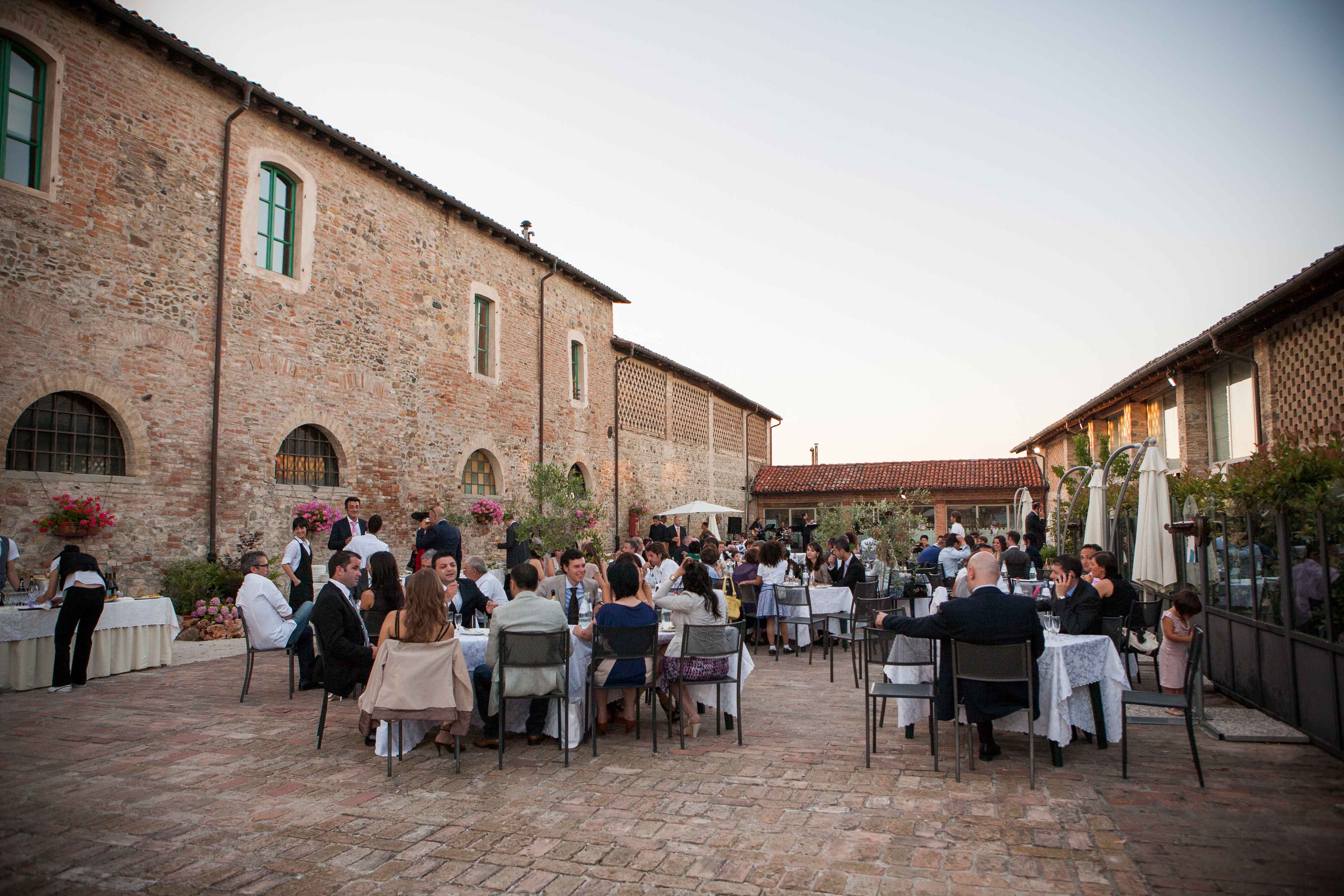 Ospiti a tavola nella corte in mattoni del ristorante al tramonto